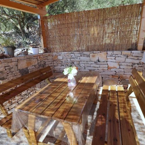 a wooden picnic table with a vase of flowers on it at Greenside Cottage Lumi in Vela Luka