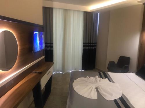a room with a bed with a tv and a table at Sette Serenity Hotel in Alanya