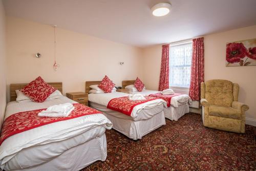una habitación de hotel con 3 camas y una silla en Daish's Hotel, en Shanklin