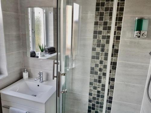 a bathroom with a sink and a shower with a mirror at Levenview Holiday Apartment Loch Lom in Balloch