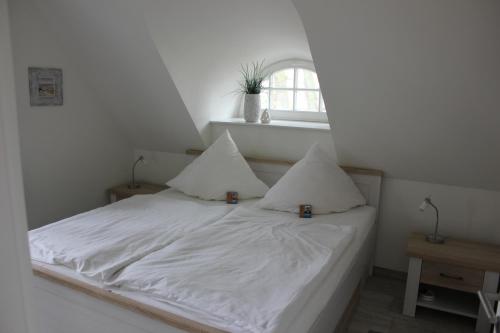 a white bed with two pillows and a window at Traditionelles Reethaus direkt an der Ostsee in Rerik