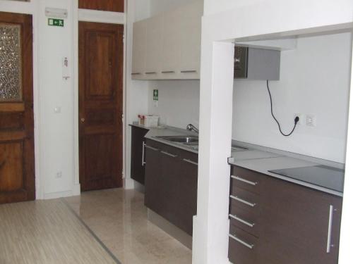 a kitchen with a sink, stove, and refrigerator at Hotel Primavera in Amadora