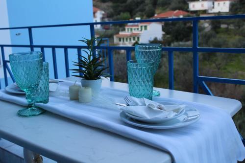 a white table with a plate and glasses on a balcony at Armenaki Apartments in Sampatiki
