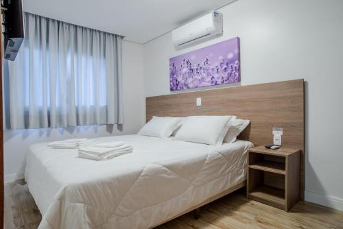 um quarto com uma grande cama branca e uma cabeceira em madeira em Monte Felice Stay - Parque da Vinícola em Gramado