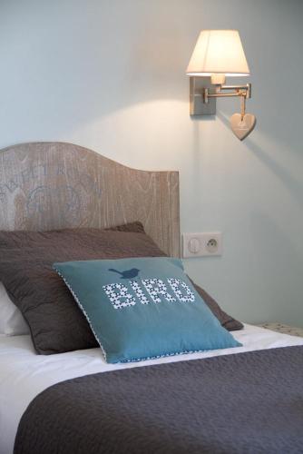 a bed with a blue pillow with an apple on it at Hôtel Le Vert Bois in Dolus d'Oléron
