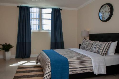 a bedroom with a large bed with a clock on the wall at Beautiful Apartment Steps Away from the Beach in Miami Beach