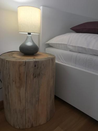 a lamp on a wooden table next to a bed at Ubytování Zahrada in Mutěnice