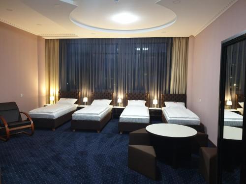a hotel room with three beds and a table and chairs at LEX Trend Hotel in Irpin'