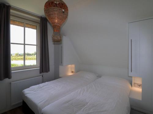 um quarto branco com uma cama e uma janela em Luxury villa with sauna and jacuzzi at the lake em Delfstrahuizen