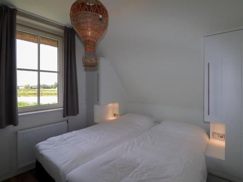 una camera da letto bianca con un letto e una finestra di Relaxing Villa with Fireplace a Delfstrahuizen