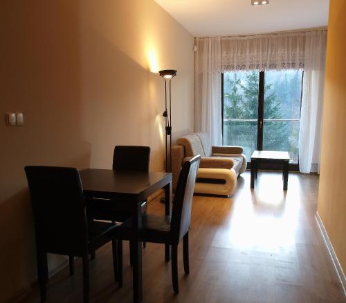uma sala de estar com uma mesa e um sofá em Apartament Na Tęczowym Wzgórzu em Wisła