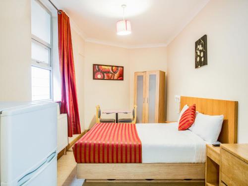 1 dormitorio con 1 cama con manta roja en Lovely Studio in London with Patio en Londres