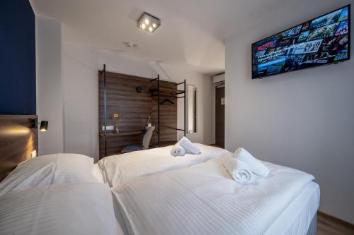 two white beds in a room with a tv on the wall at Hotel Zu Freunden in Hamm