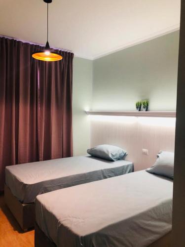 a bedroom with two beds and a window with a lamp at Sodic Westown Residence1-near Elnada hospital in ‘Izbat Yūsif Barrādah