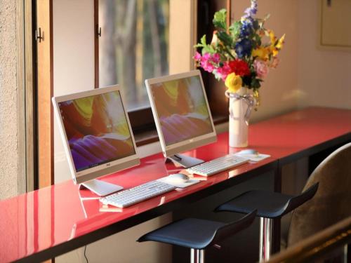 a desk with two computers and a vase of flowers at Garden hotel Shiunkaku Higashimatsuyama / Vacation STAY 77479 in Higashimatsuyama