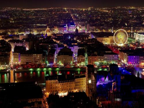 Una ciudad iluminada por la noche con una noria en Hotel Le Saint Vincent Lyon Sud en Vourles