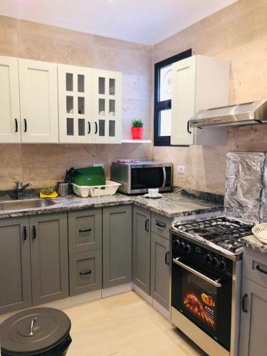a kitchen with gray cabinets and a stove top oven at Sodic Westown Residence1-near Elnada hospital in ‘Izbat Yūsif Barrādah
