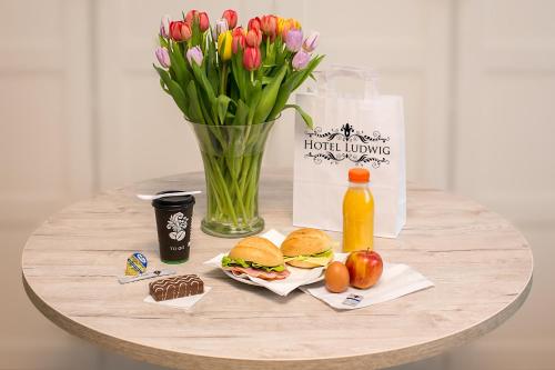 a table with a vase of flowers and a table with food and drinks at Hotel Ludwig in Munich