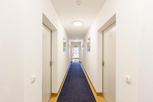 a hallway with white walls and a blue carpet at Hotel Ludwig in Munich