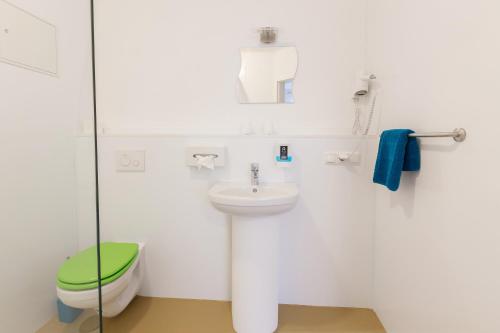 a white bathroom with a toilet and a sink at Hotel Ludwig in Munich