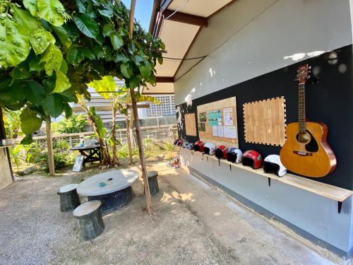 a guitar on the side of a wall with a bench at Winter House Chiang Rai in Chiang Rai