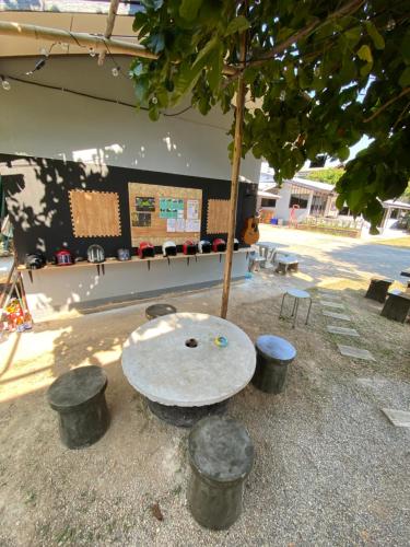 a table and stools in front of a building with a tree at Winter House Chiang Rai in Chiang Rai