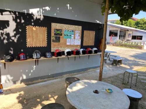 a table and some helmets on a wall with a table and chairs at Winter House Chiang Rai in Chiang Rai