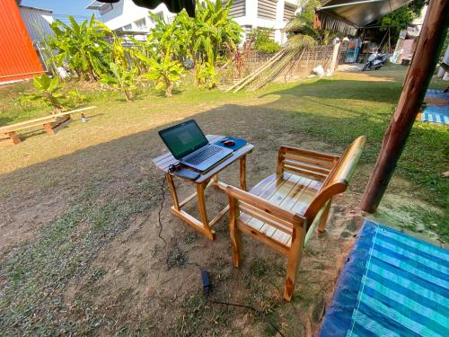 a laptop computer sitting on a table next to a chair at Winter House Chiang Rai in Chiang Rai