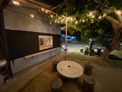 a table under a tree with a person sitting on a bench at Winter House Chiang Rai in Chiang Rai