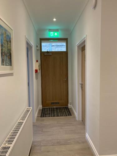 a hallway with a door with a green exit sign at Cotswold Hare in Cirencester