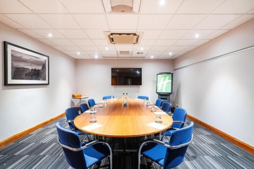 a conference room with a large wooden table and blue chairs at Holiday Inn Coventry M6, J2 by IHG in Coventry