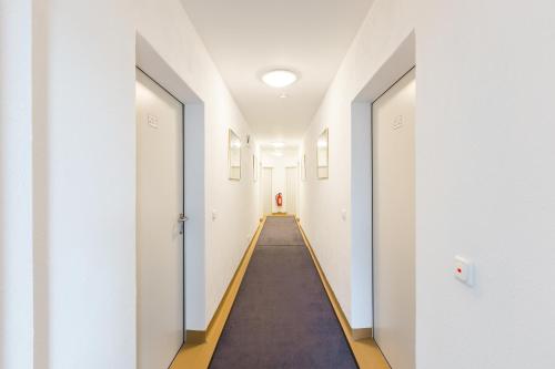 a long corridor with white walls and a long hallway at Hotel Ludwig in Munich