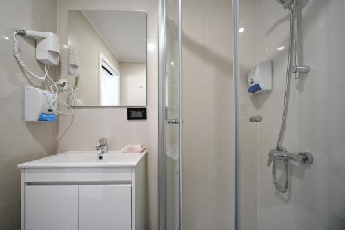 a white bathroom with a shower and a sink at Famous Crows Lisbon Suites in Lisbon