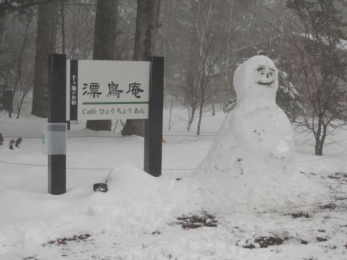 a snowman sitting next to a sign in the snow at B&B Hotel Hyochoan in Karuizawa