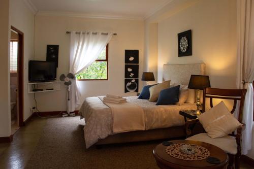 a bedroom with a bed and a couch and a window at Hartley Manor Guest House in Muldersdrift