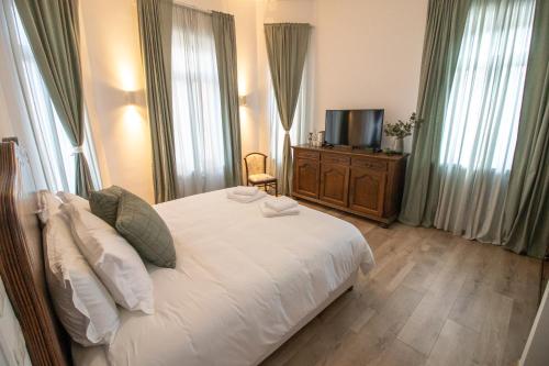 a bedroom with a white bed and a television at Seven cafe & hotel in Pogradec