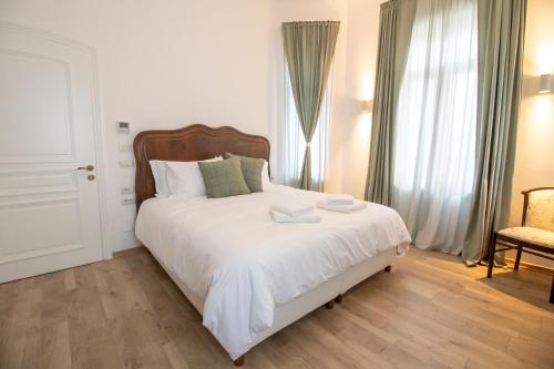 a bedroom with a bed with white sheets and a chair at Seven cafe & hotel in Pogradec