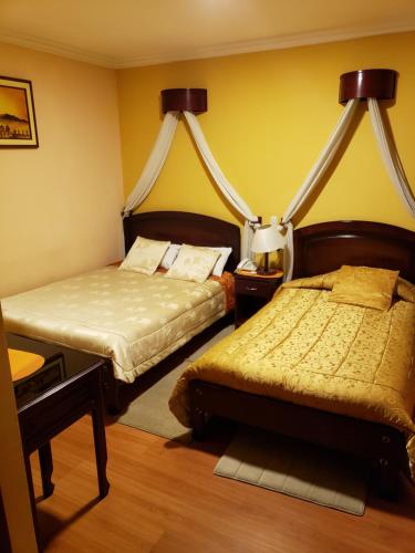 two beds in a room with yellow walls at Lloresa in Cuenca