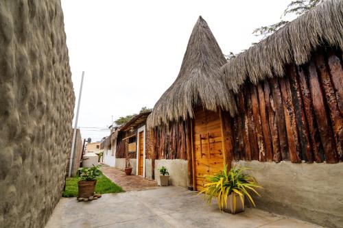 a building with a thatched roof with plants in front of it at Huluwaju Hotel in La Bocana