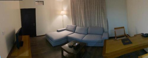 a living room with a blue couch and a table at Doolve Hotel Al Khobar in Al Khobar