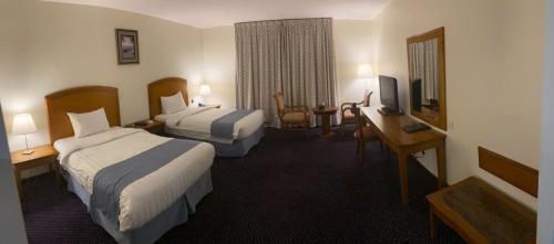 a hotel room with two beds and a desk at Doolve Hotel Al Khobar in Al Khobar