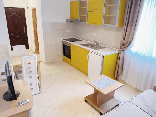 a small kitchen with yellow cabinets and a sink at Apartments Sneki in Baošići