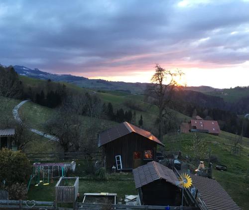 a house on a hill with the sunset in the background at 3,5 Zimmerferienwohnung Schwalbenäscht Rüeggisberg in Rüeggisberg