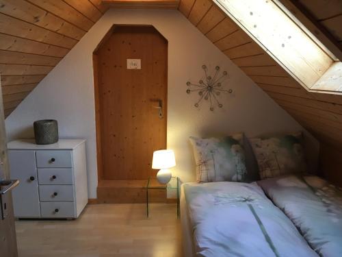 a attic bedroom with a bed and a door at 3,5 Zimmerferienwohnung Schwalbenäscht Rüeggisberg in Rüeggisberg