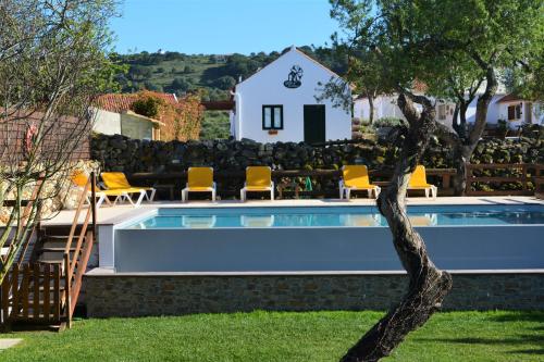 a pool with chairs and a house in the background at Quinta do Tio Viagem in Quinta do Anjo