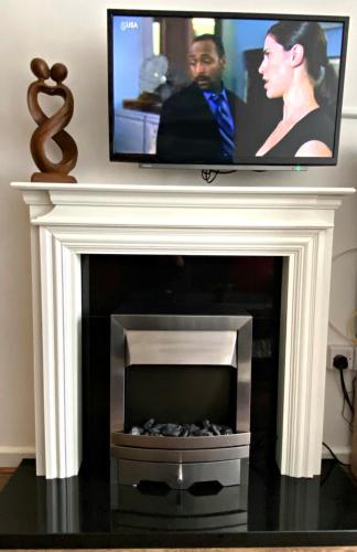 a tv over a fireplace with a television above it at Serviced Apartment Bristol One-Bedroom Southmead Hospital MOD Airbus in Bristol