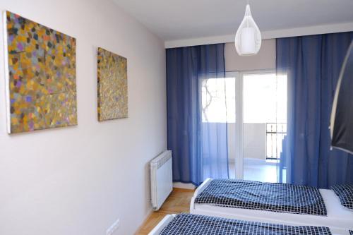 een slaapkamer met 2 bedden en een raam met blauwe gordijnen bij HEDONA in Visoko