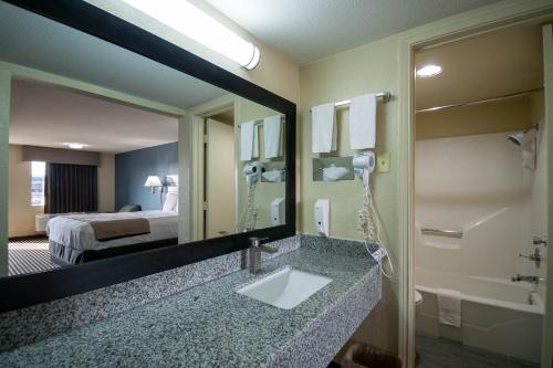 a bathroom with a sink and a mirror and a bed at Countryside Inn in Kaufman