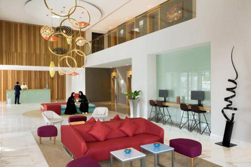 a living room with a red couch and purple chairs at Adagio Jeddah City Center in Jeddah