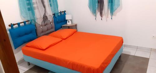 ein Schlafzimmer mit einem orangenen Bett in einem Zimmer in der Unterkunft Les gîtes des 500 pas in Sainte-Anne